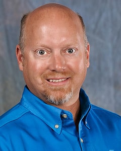 Mr. Fettes' headshot in a blue shirt with co-op branding