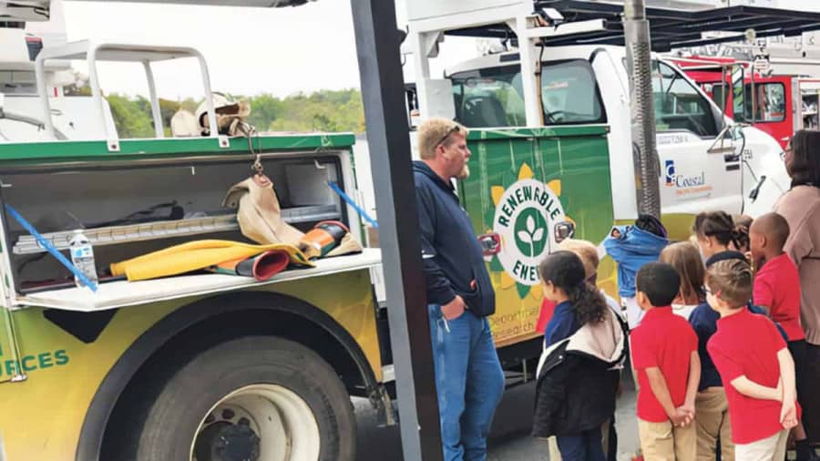 Mr. Duke in front of a Coastal Electric Cooperative utility truck with children and teacher looking on