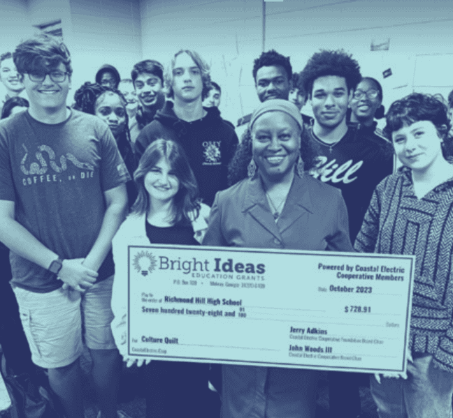 Teacher and students pose with a Bright Ideas check