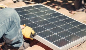 A worker's gloved hands installing a solar panel
