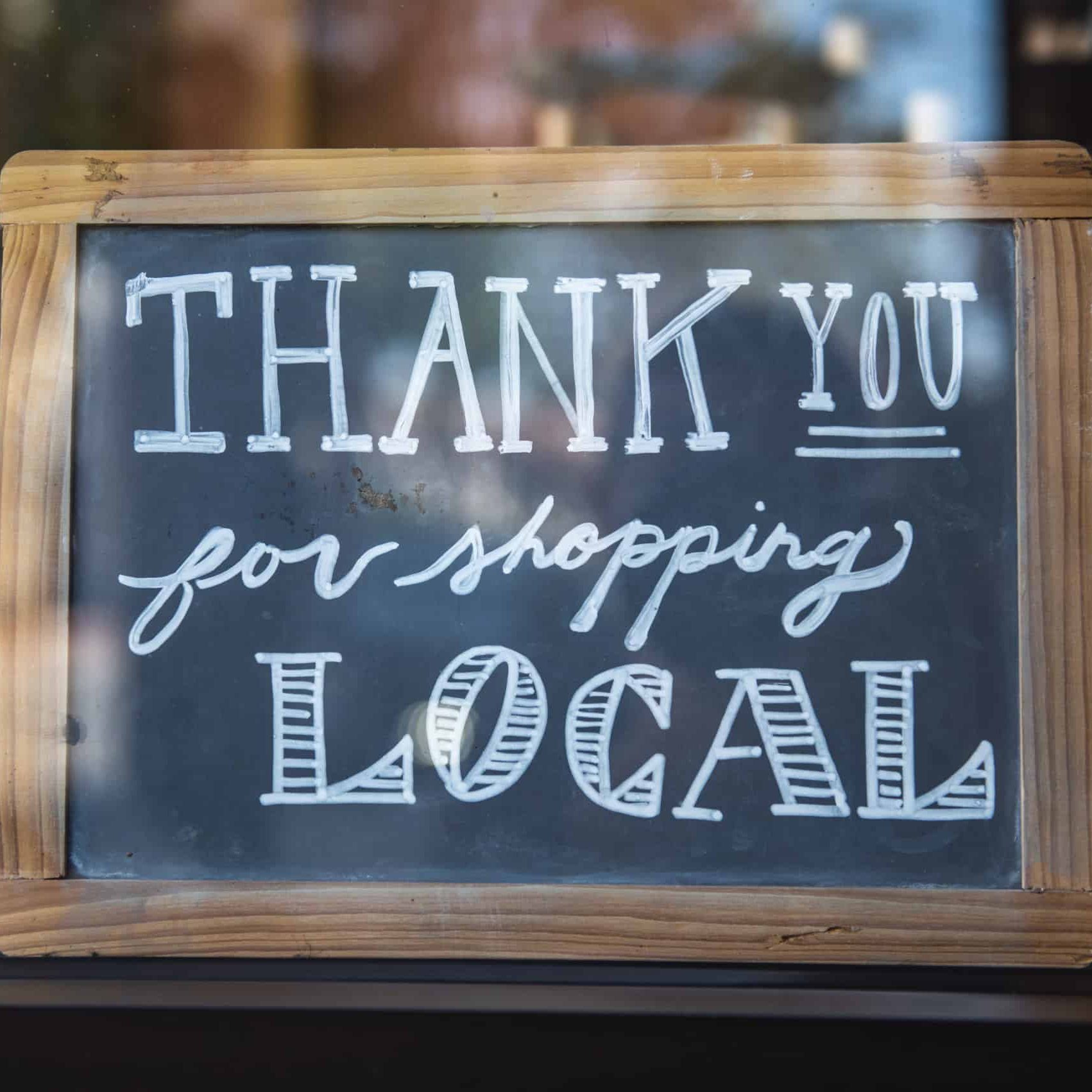 The message on a chalkboard thanks customers for shopping local