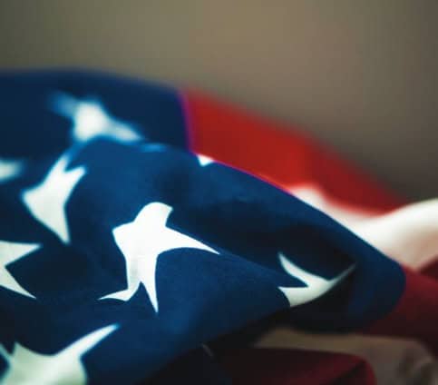 A close-up of a folded American flag, showcasing star designs on a blue background with parts of visible red and white stripes.