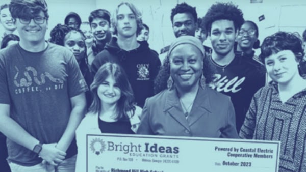 Teacher and students pose with a Bright Ideas check