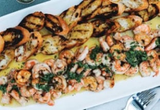 Grilled shrimp are fanned out on a plate