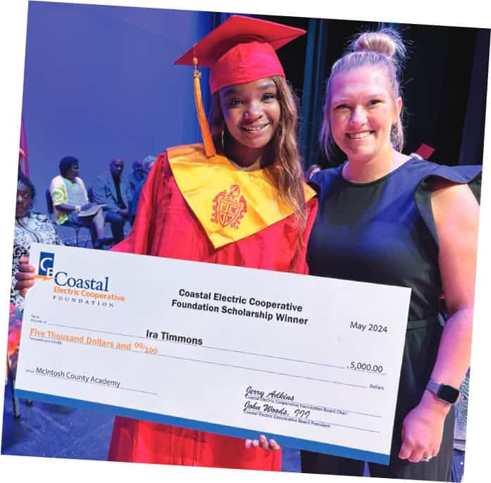 A graduating student smiles as she receives a scholarship check