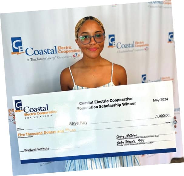 A scholarship winner poses with her oversized check.