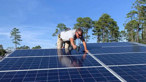 A worker is shown installing solar panels