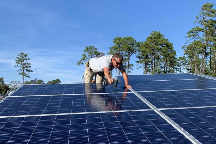 A worker is shown installing solar panels